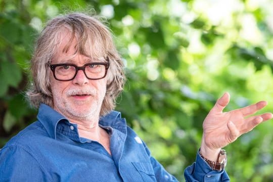 Musiker Helge Schneider spricht in seinem Garten mit einem Journalisten.