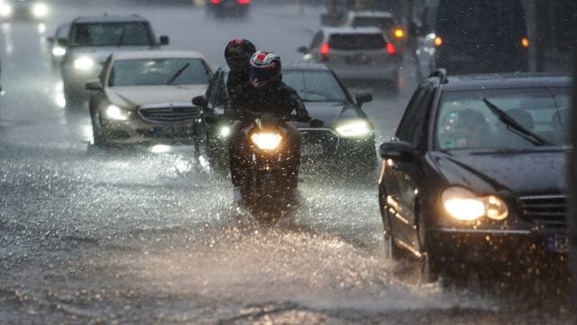 Autos und Motorräder fahren bei starkem Regen über die Straße