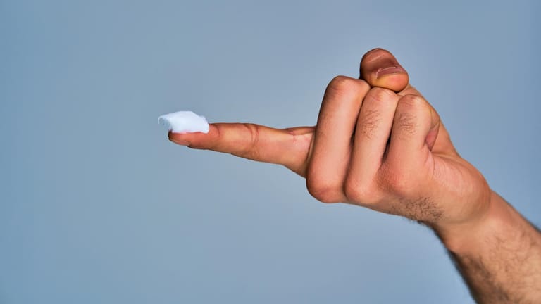 Salbe auf einem Finger: Bei einer Analthrombose hilft oft eine Behandlung mit Salben oder Cremes, um die Schmerzen zu lindern.