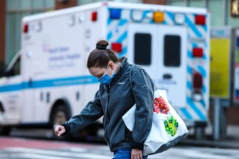 Eine Frau läuft mit gesenktem Kopf an einem Krankenwagen vorbei: Die Coronalage spitzt sich derzeit in einigen Bundesstaaten wieder zu.