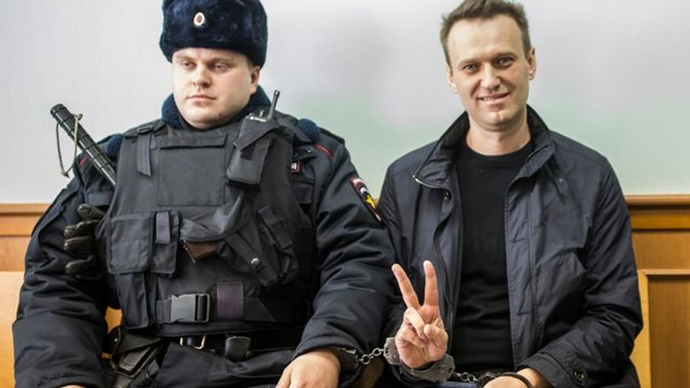 Kremlgegner Alexej Nawalny (r) zeigt ein Victory-Zeichen, während er neben einem Sicherheitsbeamten im Gericht sitzt (Archivbild).