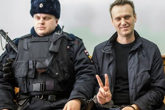 Kremlgegner Alexej Nawalny (r) zeigt ein Victory-Zeichen, während er neben einem Sicherheitsbeamten im Gericht sitzt (Archivbild).