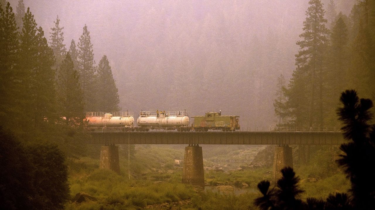 Ein Löschzug überquert eine Brücke in Kalifornien und versprüht Löschmittel auf Gleise und umliegendes Land.