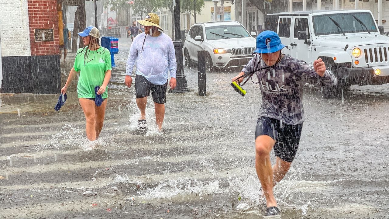 Fußgänger waten in Key West durch Hochwasser an einer Kreuzung.