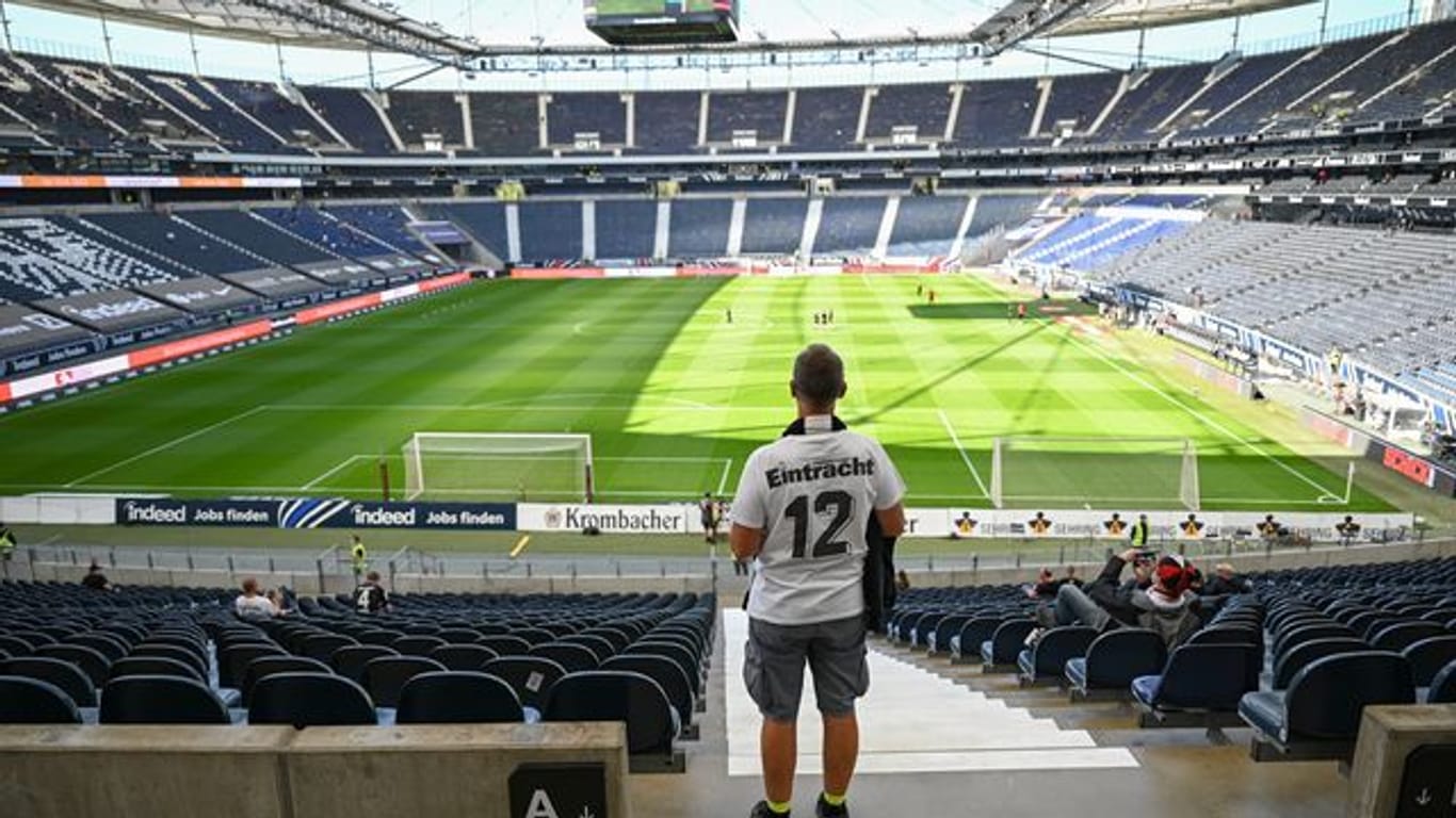 Ein Fan von Eintracht Frankfurt sucht auf der spärlich besetzten Tribüne nach seinem Sitzplatz.