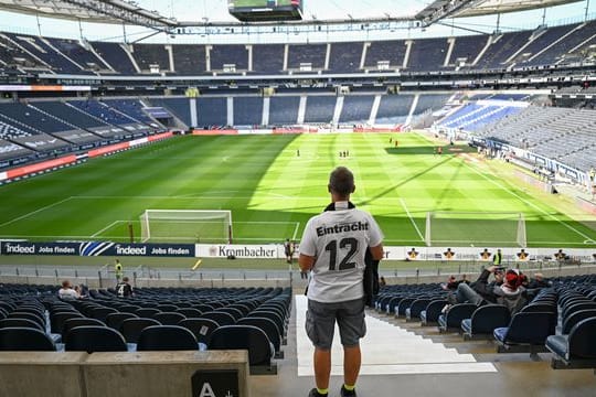 Ein Fan von Eintracht Frankfurt sucht auf der spärlich besetzten Tribüne nach seinem Sitzplatz.