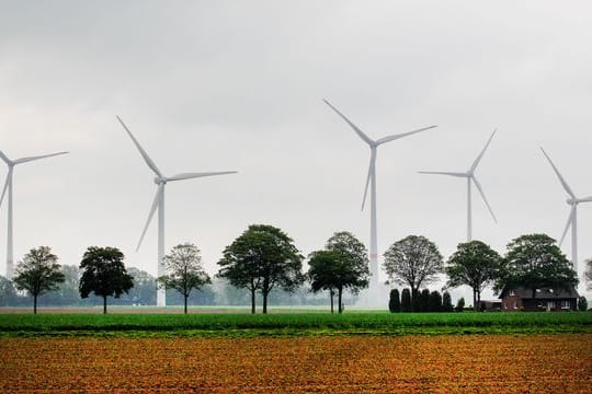 Windkraftanlagen drehen sich hinter Feldern