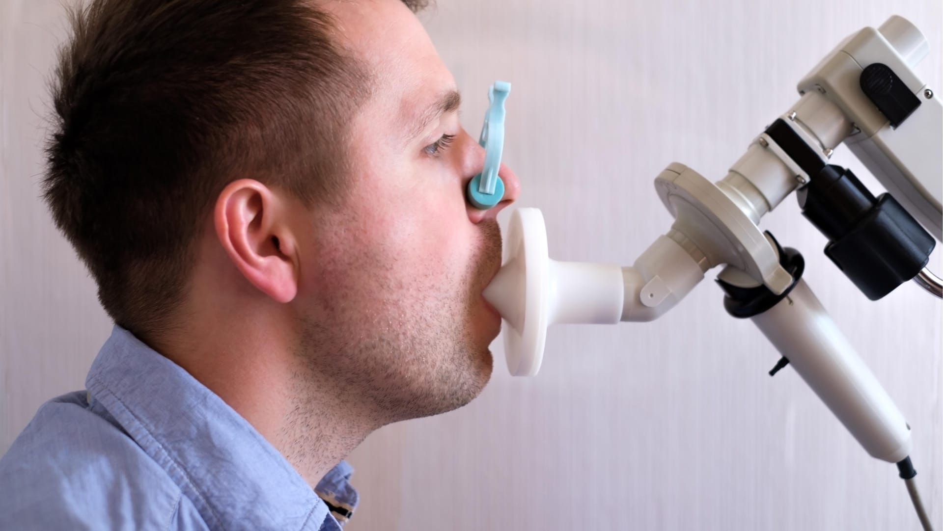 Mann beim Lungenfunktionstest: Bei der Spirometrie atmet man nach Anweisung in ein Mundstück, wobei Menge und Geschwindigkeit der ein- und ausgeatmeten Luft erfasst werden.