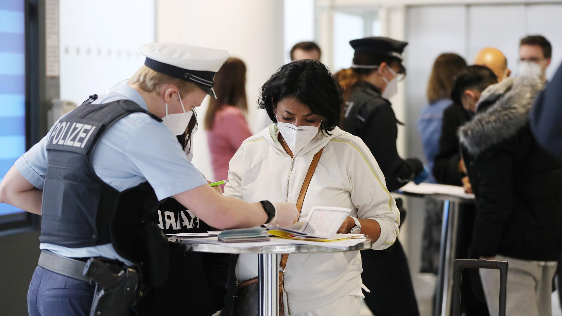 Eine Polizistin hilf Flugreisenden beim Ausfüllen der Einreiseformulare (Symbolbild): Ob tatsächlich alle Einreisenden aus Risikogebieten ein solches Formular ausgefüllt haben, scheint wenig kontrolliert zu werden.