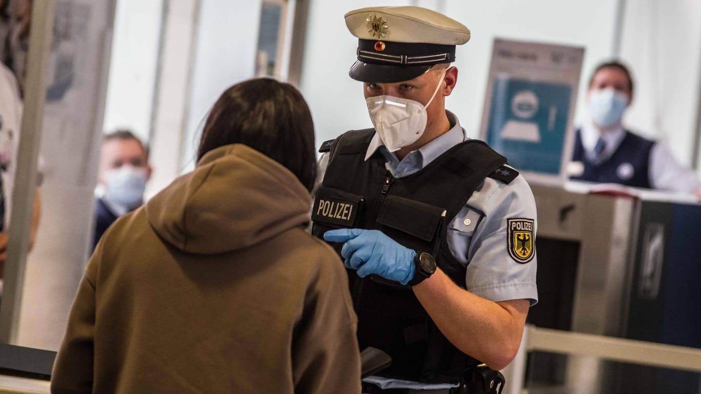 Ein Polizist kontrolliert eine Flugreisende (Symbolbild): An den Airports ist die Bundespolizei für die Kontrolle der digitalen Anmelde- sowie Nachweispflicht zuständig.