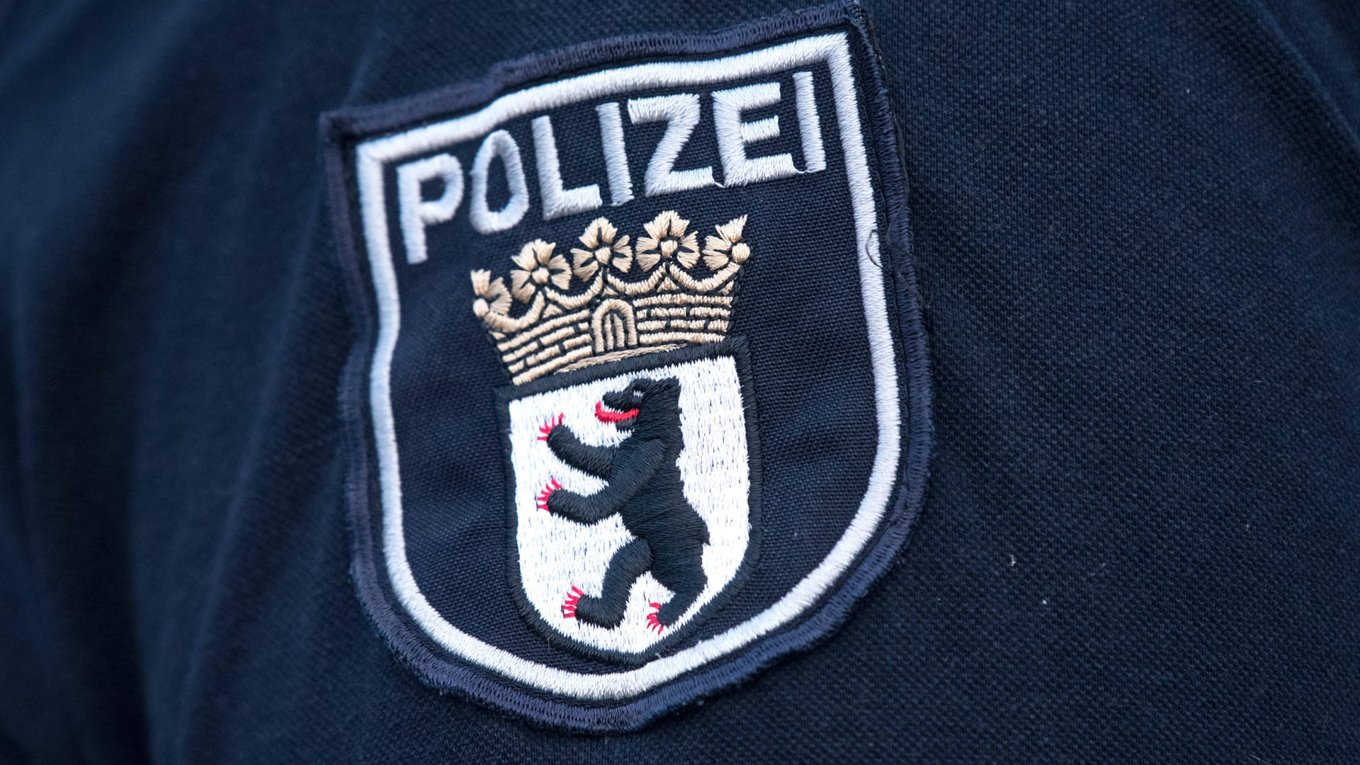 Das Logo der Berliner Polizei auf einer Uniform (Symbolbild): In Berlin durchsucht die Polizei Dutzende Objekte.