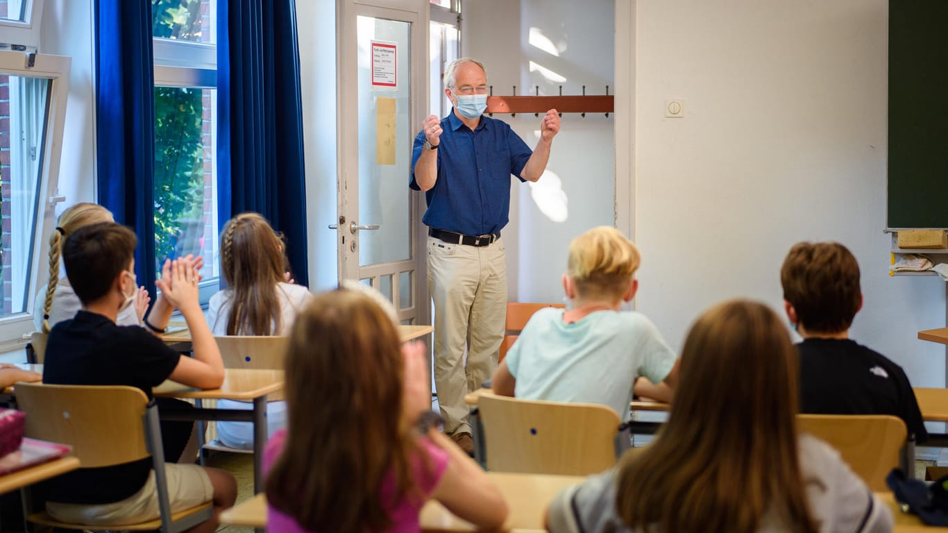 Ein Kieler Schulleiter begrüßt Schülerinnen und Schüler am ersten Tag des Schuljahres: Auch zwölf Monate später prägen Schutzmaßnahmen gegen das Coronavirus die Unterrichtsbedingungen.