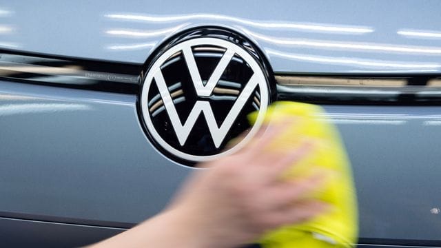 Eine Mitarbeiterin poliert ein Fahrzeug von VW