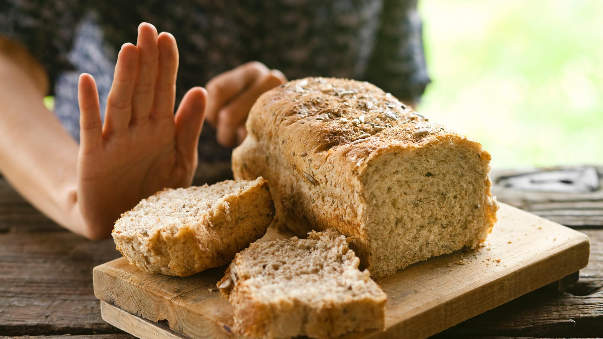 Ein angeschnittenes Brot und eine Hand mit ablehnender Geste.