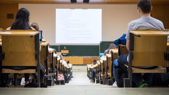 Studentinnen und Studenten sitzen während einer Vorlesung in einem Hörsaal.