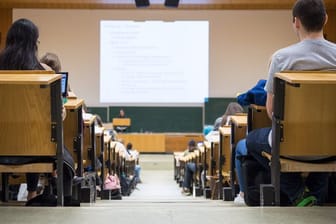 Studentinnen und Studenten sitzen während einer Vorlesung in einem Hörsaal.