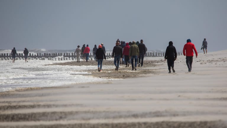 Strandspaziergänger auf der Nordsee-Insel Norderney: An den Küstenregionen bleibt es auch morgen noch stürmisch.