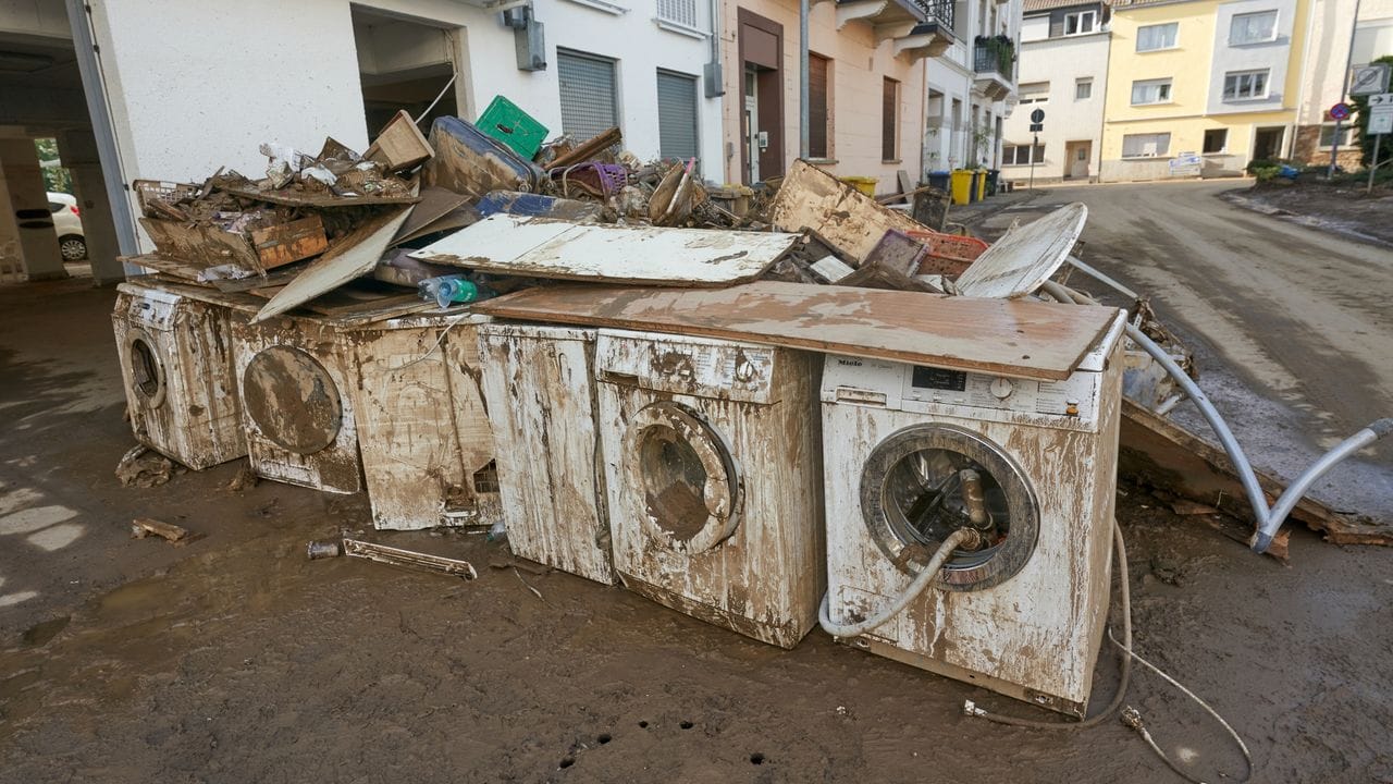 Zerstörte Waschmaschinen stehen vor einem Wohnhaus.