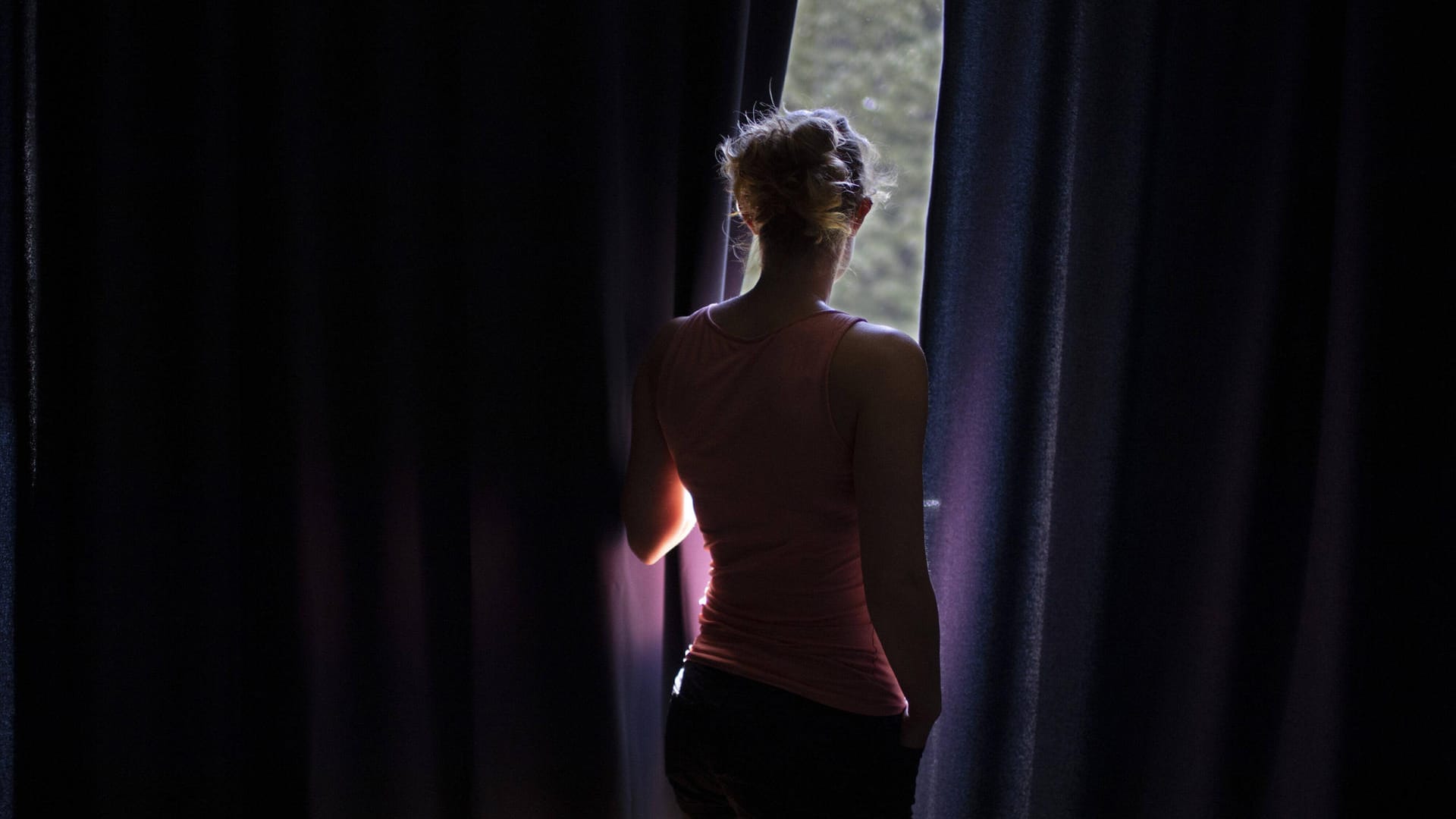 Eine Frau schaut aus einem Fenster (Symbolbild): Gewalt in Beziehungen sei ein Problem in der Mitte der Gesellschaft, wie ein Kölner Streetworker sagt.