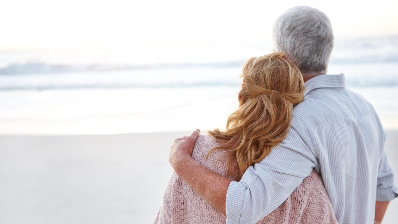 Älteres Paar Arm in Arm am Strand: Aussicht auf Heilung besteht bei COPD nicht – doch der richtige Umgang mit der Krankheit hilft, das Leben so gut es geht zu genießen.