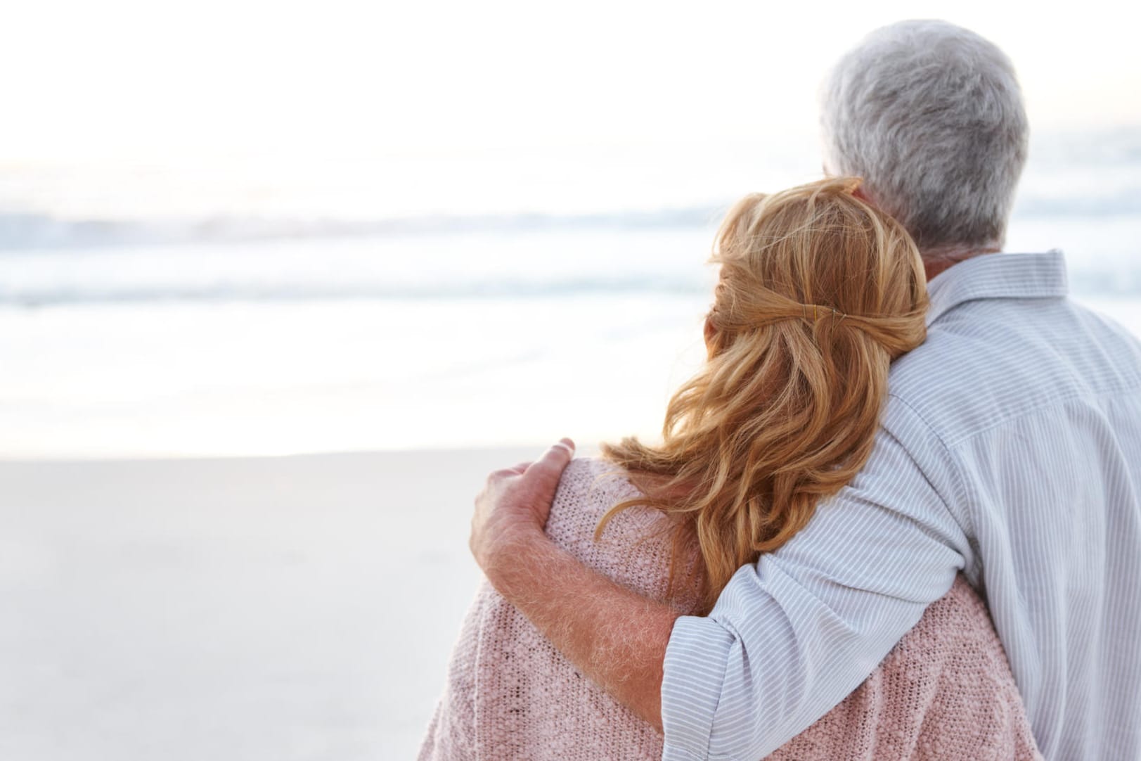 Älteres Paar Arm in Arm am Strand: Aussicht auf Heilung besteht bei COPD nicht – doch der richtige Umgang mit der Krankheit hilft, das Leben so gut es geht zu genießen.