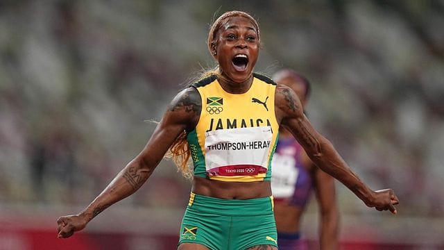 Jamaikas Elaine Thompson-Herah feiert olympisches Gold über 100 Meter. Jamaikas Elaine Thompson-Herah feiert olympisches Gold über 100 Meter.