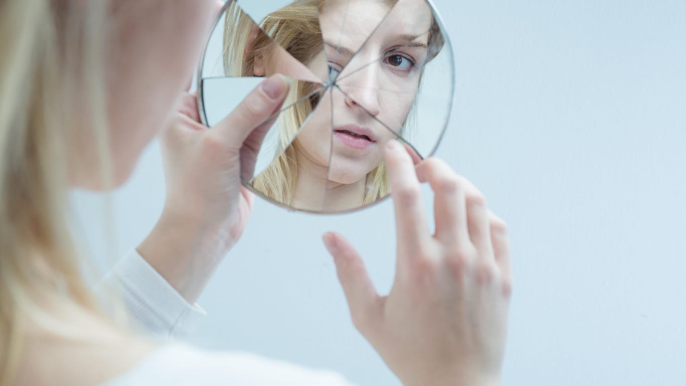 Frau schaut in ihre Spiegelbilder in einem zerbrochenen Spiegel
