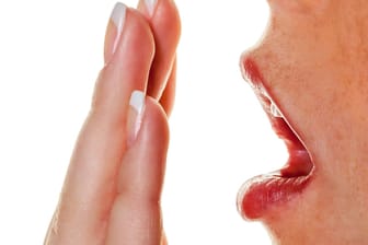 Hand vor dem Mund: Mundgeruch kann nicht nur durch mangelnde Zahnhygiene ausgelöst werden, sondern auch durch Krankheiten.