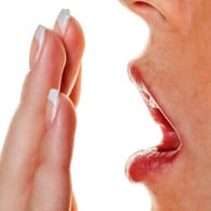Hand vor dem Mund: Mundgeruch kann nicht nur durch mangelnde Zahnhygiene ausgelöst werden, sondern auch durch Krankheiten.