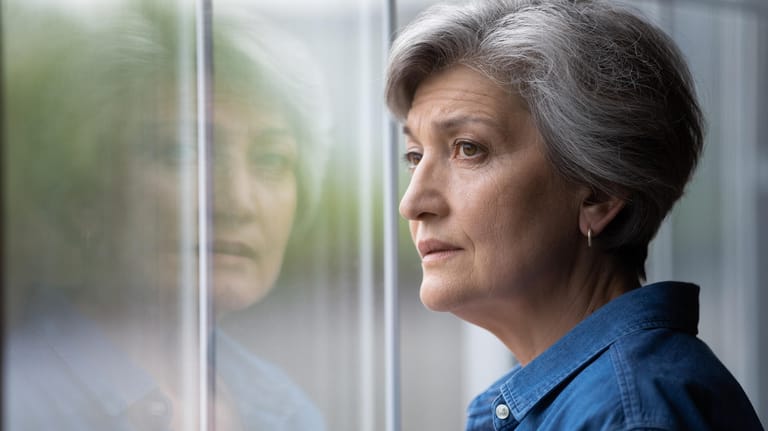 Ältere Frau schaut aus dem Fenster (Symbolbild): Die gesetzliche Rente steht vor einem Finanzproblem.