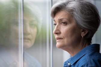 Ältere Frau schaut aus dem Fenster (Symbolbild): Die gesetzliche Rente steht vor einem Finanzproblem.