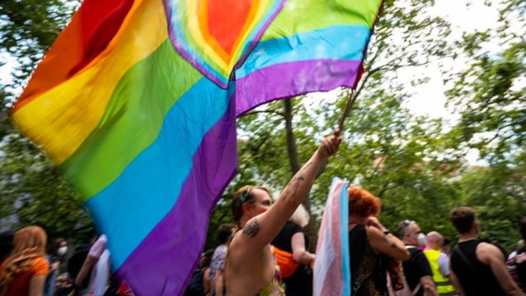 Ein Teilnehmer der "CSD Berlin Pride" trägt eine Regenbogenfarbene Flagge mit einem Herz.