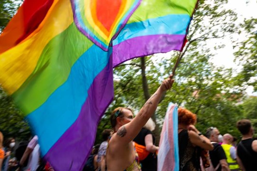 Ein Teilnehmer der "CSD Berlin Pride" trägt eine Regenbogenfarbene Flagge mit einem Herz.