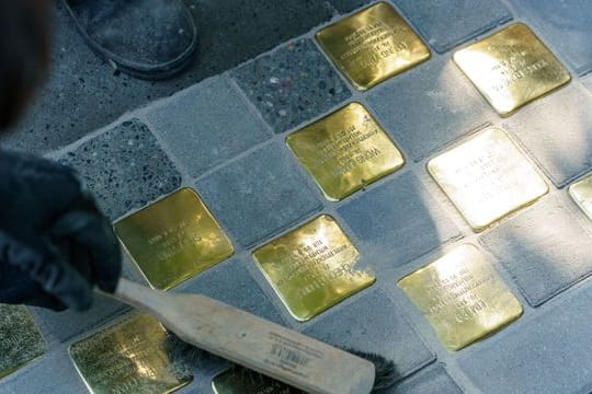 Künstler Gunter Demnig fegt die von ihm verlegten Stolpersteine in der Hamburger Talstraße ab.
