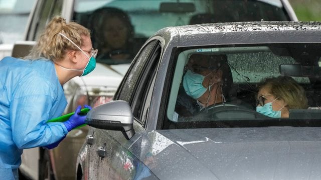 Eine Mitarbeiterin einer Teststation bereitet Autofahrer auf einen COVID-19-Test vor.