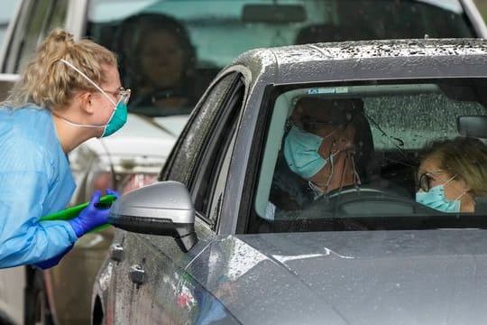 Eine Mitarbeiterin einer Teststation bereitet Autofahrer auf einen COVID-19-Test vor.