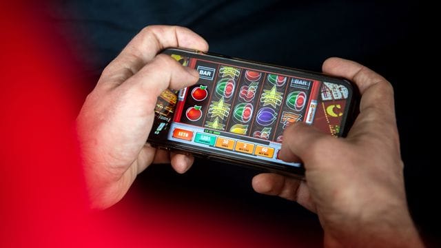 Auf einem Smartphone spielt ein Mann ein Online-Spiel.