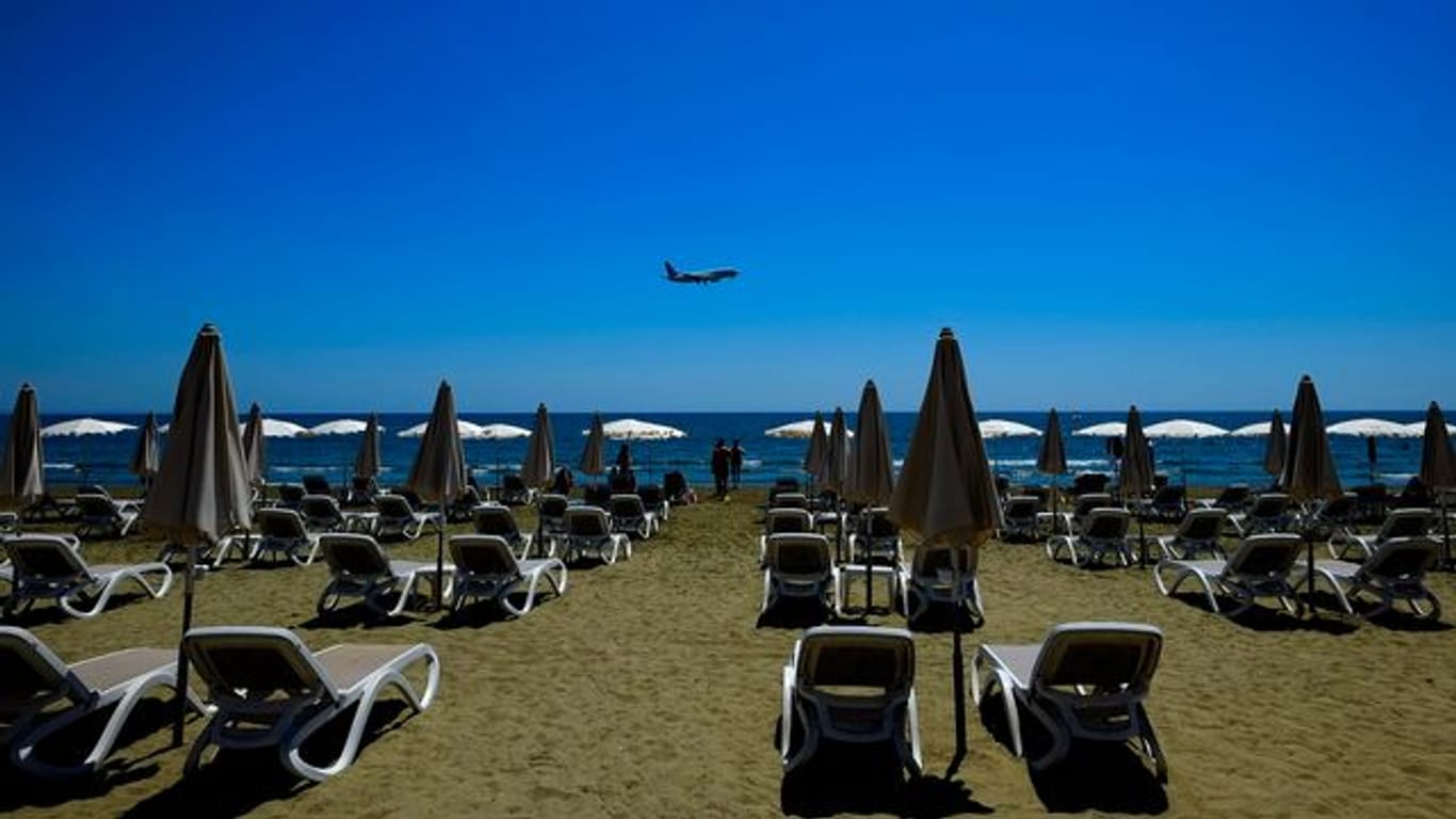 Einige Menschen besuchen den Makenzi-Strand, während sich im Hintergrund ein Flugzeug auf die Landung am internationalen Flughafen Larnaka vorbereitet.