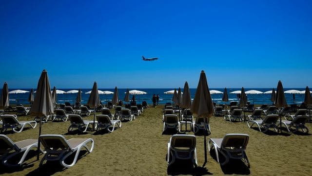 Einige Menschen besuchen den Makenzi-Strand, während sich im Hintergrund ein Flugzeug auf die Landung am internationalen Flughafen Larnaka vorbereitet. Einige Menschen besuchen den Makenzi-Strand, während sich im Hintergrund ein Flugzeug auf die Landung am internationalen Flughafen Larnaka vorbereitet.