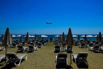Einige Menschen besuchen den Makenzi-Strand, während sich im Hintergrund ein Flugzeug auf die Landung am internationalen Flughafen Larnaka vorbereitet.