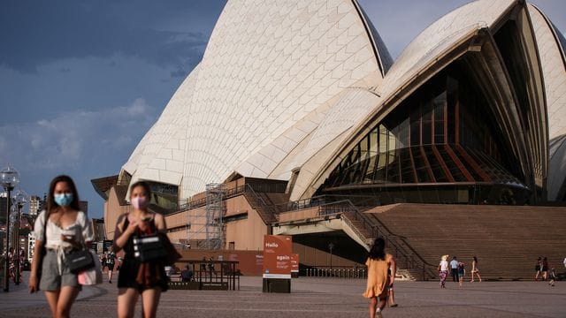 Passanten mit Mund-Nasen-Bedeckung gehen am berühmten Opernhaus in Sydney vorbei. Passanten mit Mund-Nasen-Bedeckung gehen am berühmten Opernhaus in Sydney vorbei.