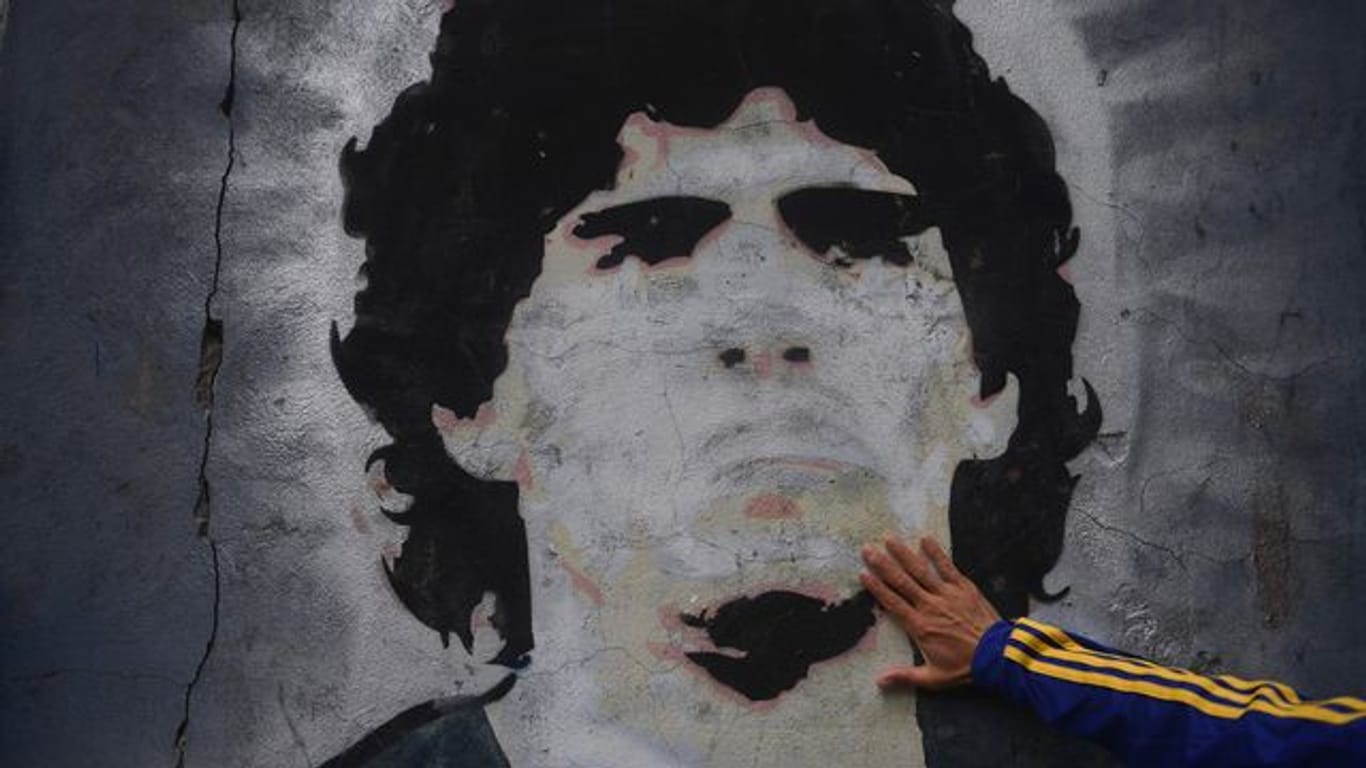 Ein Fan trauert vor einem Wandgemälde mit der Abbildung des ehemaligen Fußballstars Maradona.