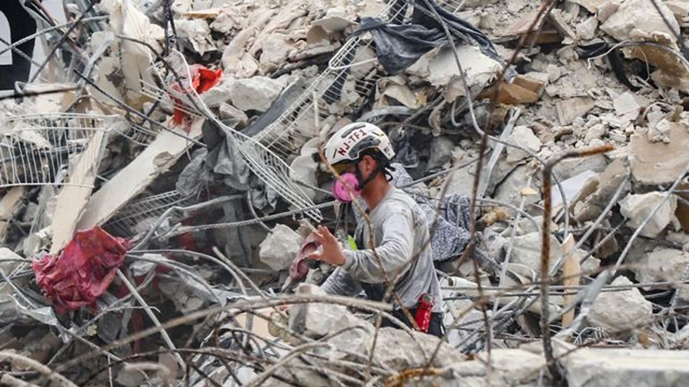 Rettungskräfte arbeiten sich durch die Trümmern des teilweise eingestürzten Wohnkomplexes.