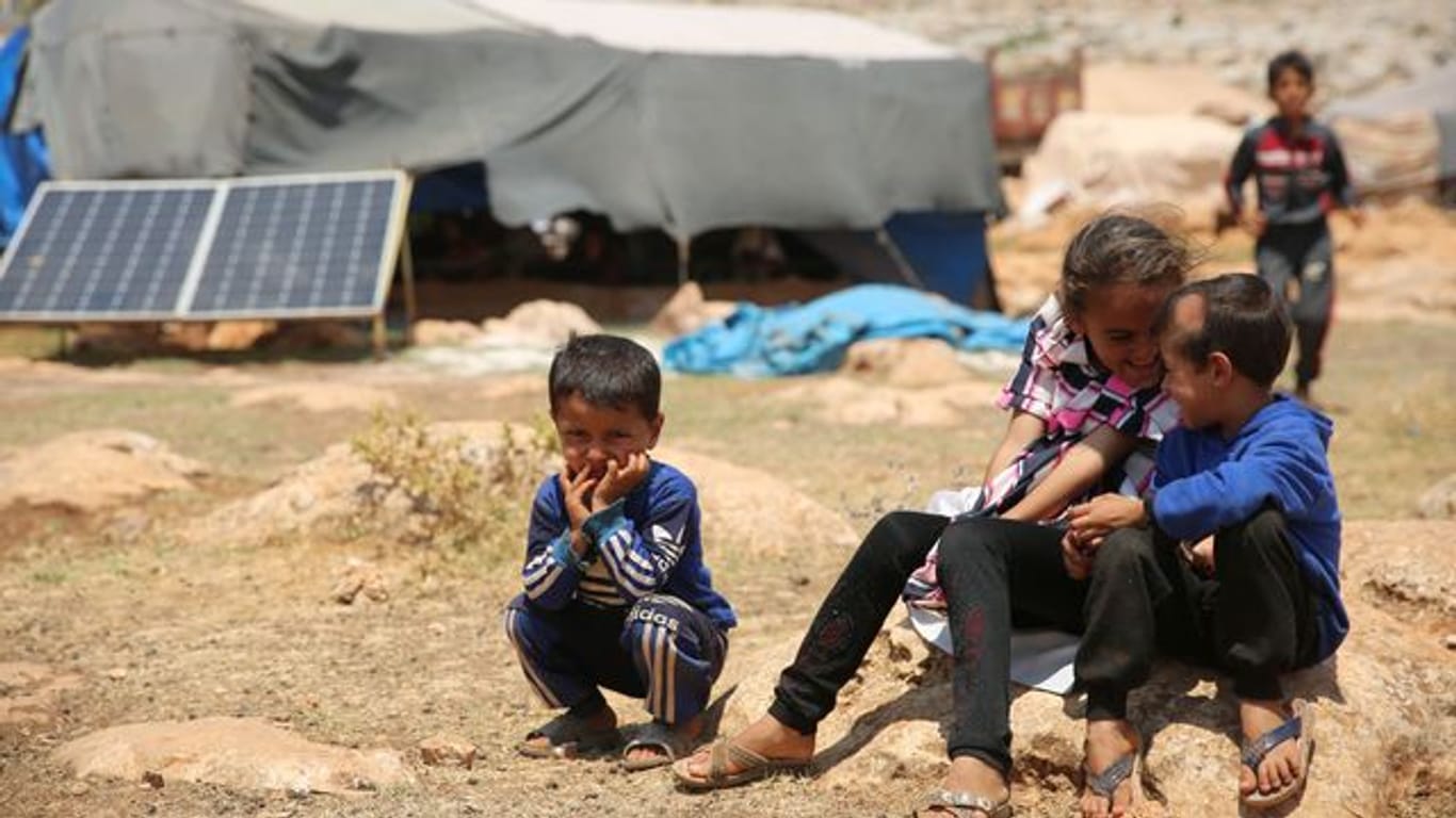 Geflüchtete Kinder sitzen in einem Flüchtlingslager nordwestlich von Aleppo auf einem Stein.