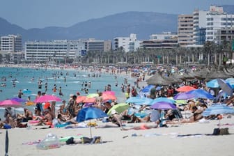 Touristen genießen die Sonne am Strand von Arenal.