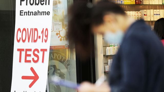 Eine Frau füllt vor einer Apotheke ein Formular für einen Covid-19-Test aus. Eine Frau füllt vor einer Apotheke ein Formular für einen Covid-19-Test aus.