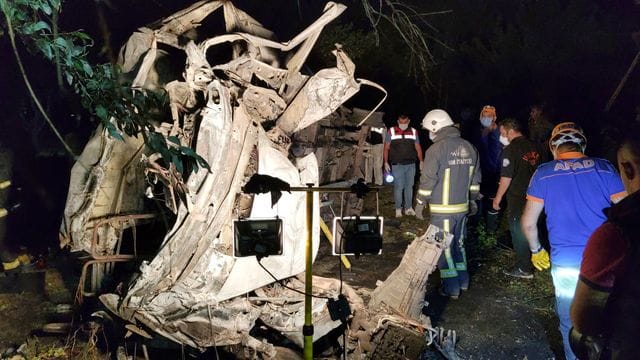 Rettungskräfte stehen neben einem ausgebrannten Wrack eines Kleinbusses, der beim Transport von Migranten in einen Graben gestürzt und dann in Brand geraten sein soll. Rettungskräfte stehen neben einem ausgebrannten Wrack eines Kleinbusses, der beim Transport von Migranten in einen Graben gestürzt und dann in Brand geraten sein soll.