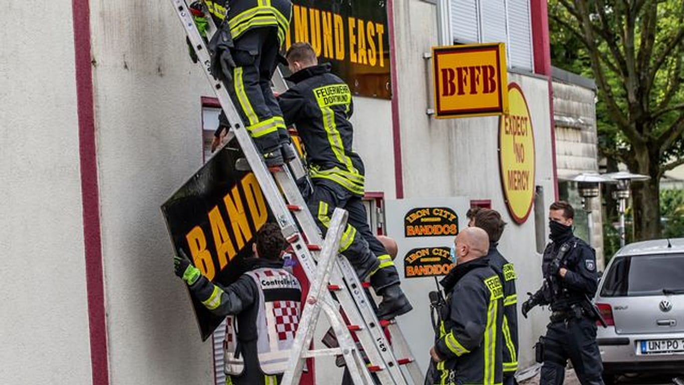 Feuerwehrleute entfernen unter Polizeischutz ein Schild am Vereinsheim der Rockergruppe "Bandidos".