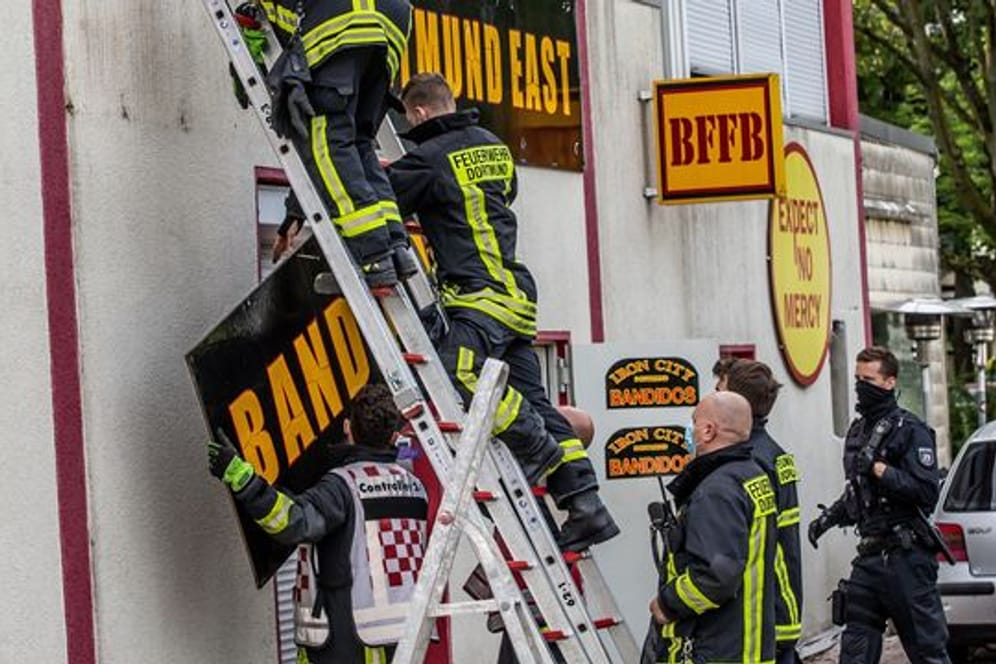 Feuerwehrleute entfernen unter Polizeischutz ein Schild am Vereinsheim der Rockergruppe "Bandidos".