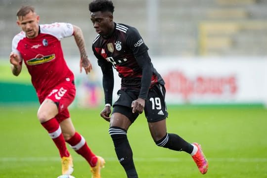 Bayerns Alphonso Davies (r) im Laufduell mit Freiburgs Jonathan Schmid.